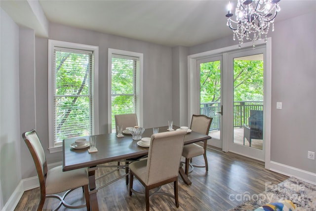 dining space with dark wood-type flooring, a wealth of natural light, and an inviting chandelier