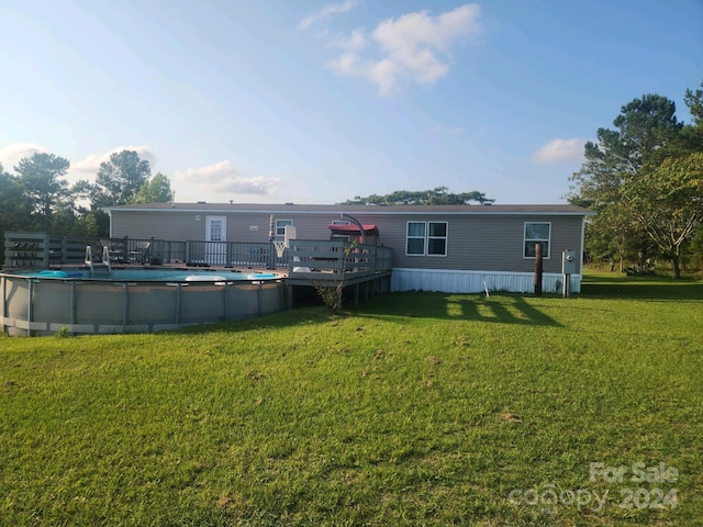 rear view of house with a swimming pool side deck and a lawn