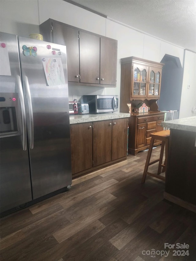 kitchen featuring stainless steel appliances, dark hardwood / wood-style floors, and a textured ceiling