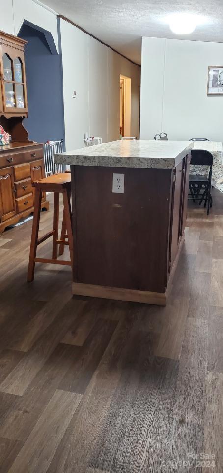 kitchen with dark hardwood / wood-style flooring, a kitchen island, and a textured ceiling