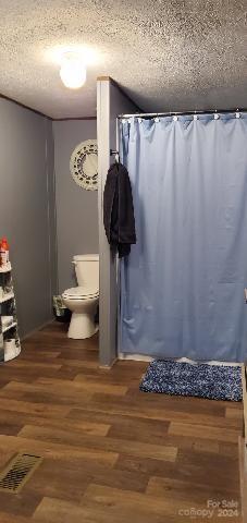 bathroom with hardwood / wood-style floors, toilet, and a textured ceiling