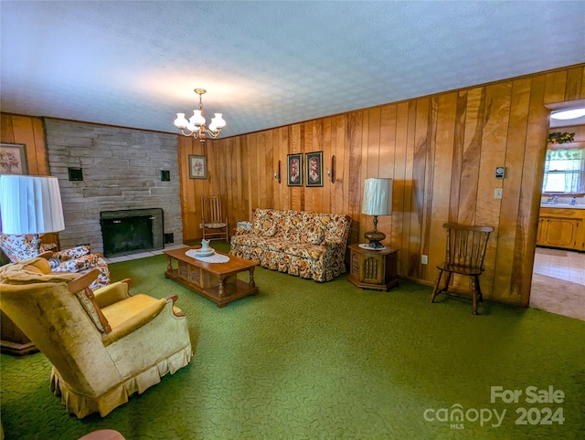 carpeted living room with a stone fireplace, wooden walls, sink, a chandelier, and a textured ceiling