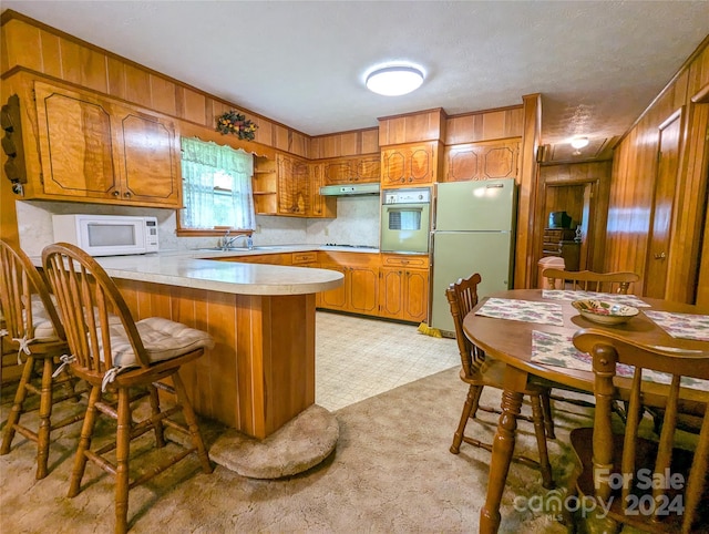 kitchen featuring refrigerator, sink, wall oven, kitchen peninsula, and gas stovetop