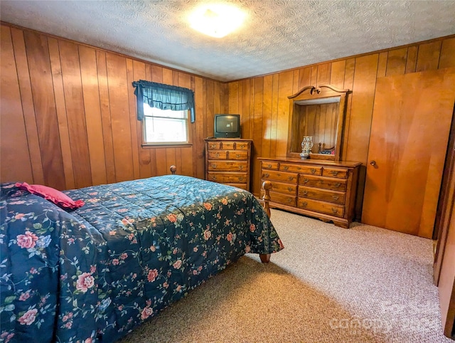 bedroom featuring carpet floors, a textured ceiling, and wood walls