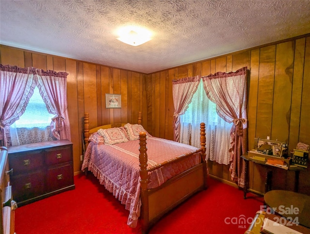 bedroom featuring wooden walls, carpet, and a textured ceiling