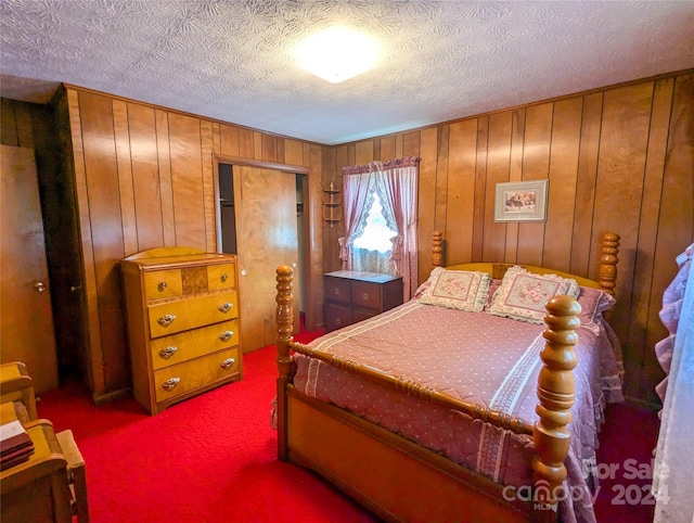 bedroom featuring wooden walls, a textured ceiling, and carpet flooring