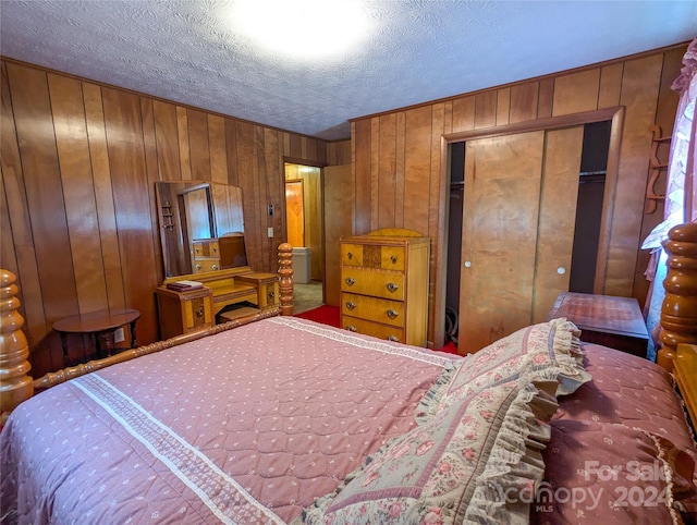 bedroom featuring wooden walls and a textured ceiling