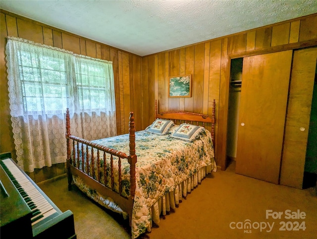 bedroom featuring carpet floors, a closet, a textured ceiling, and wood walls