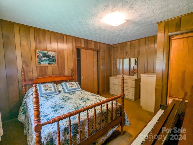 carpeted bedroom with a closet, a textured ceiling, and wood walls