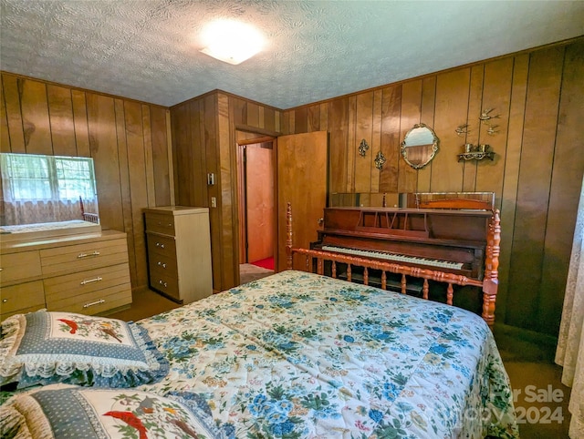 bedroom with wooden walls and a textured ceiling