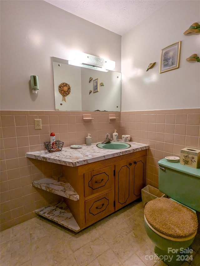 bathroom featuring tile walls, tile patterned flooring, vanity, toilet, and a textured ceiling