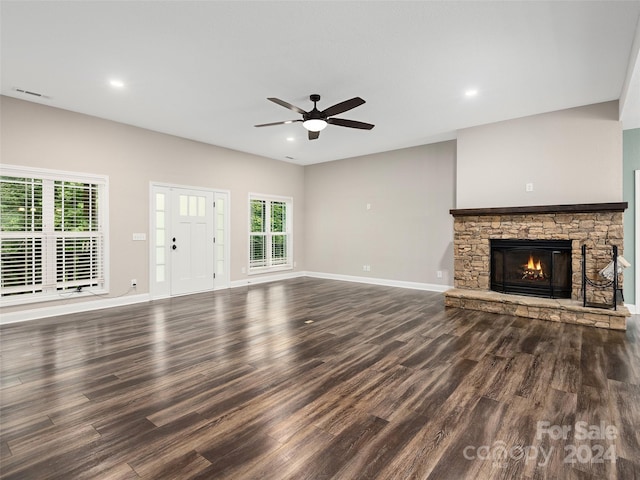 unfurnished living room with ceiling fan, hardwood / wood-style flooring, and a stone fireplace