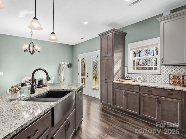 kitchen featuring visible vents, dark wood-style flooring, dark brown cabinets, stainless steel dishwasher, and backsplash