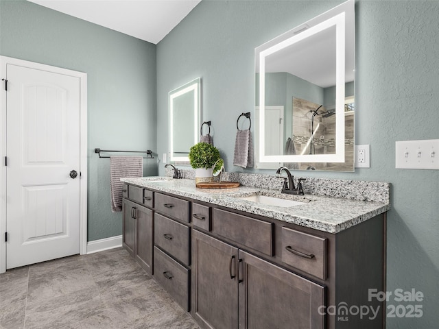 full bath featuring a textured wall, walk in shower, a sink, and double vanity