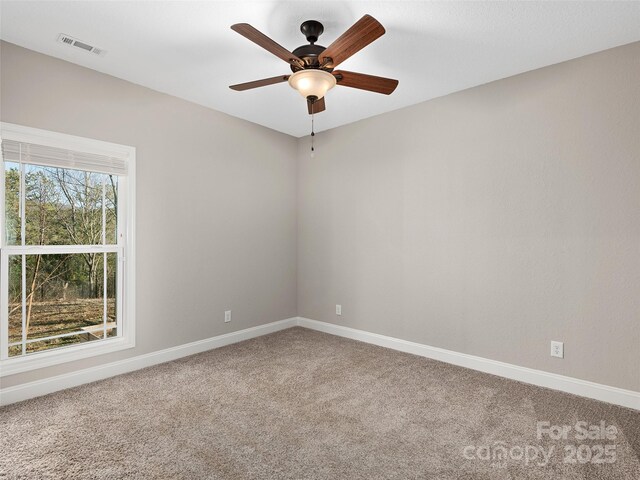 carpeted spare room featuring a ceiling fan, visible vents, and baseboards