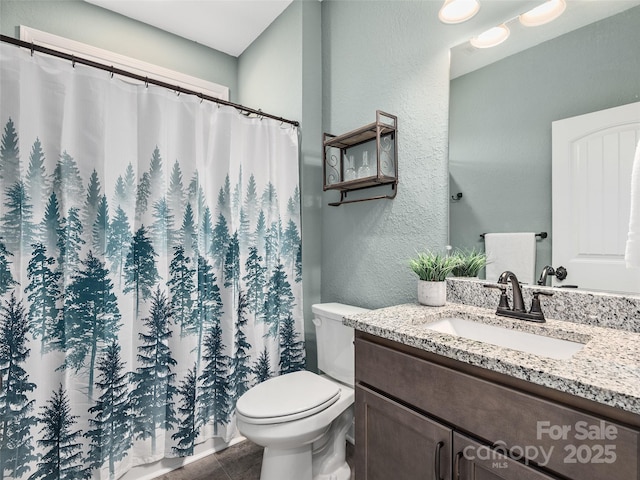 full bath featuring a shower with shower curtain, a textured wall, vanity, and toilet