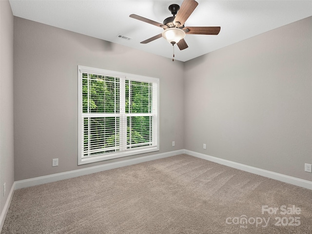 carpeted spare room featuring visible vents, baseboards, and a ceiling fan