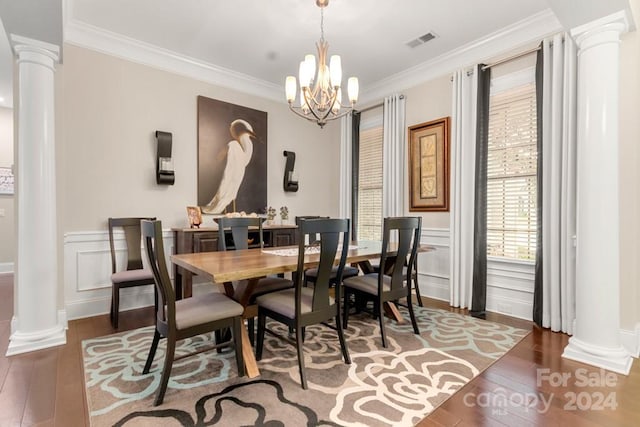 dining room featuring crown molding, dark hardwood / wood-style floors, a chandelier, and ornate columns