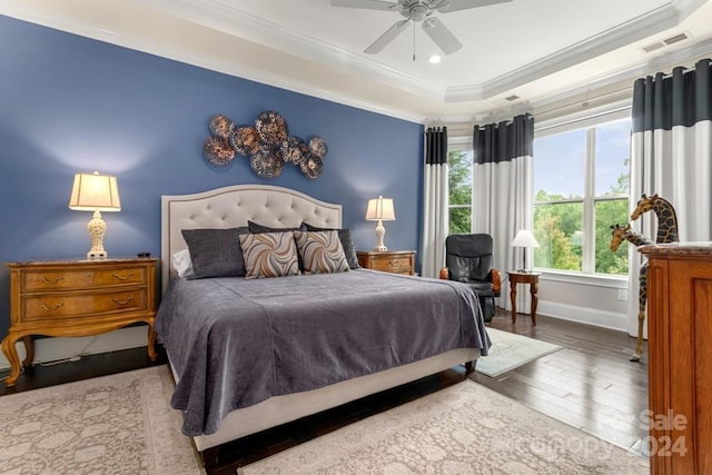 bedroom featuring wood-type flooring, crown molding, ceiling fan, and a tray ceiling