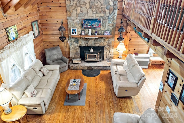 living room with wooden walls, wood-type flooring, a wood stove, and beam ceiling