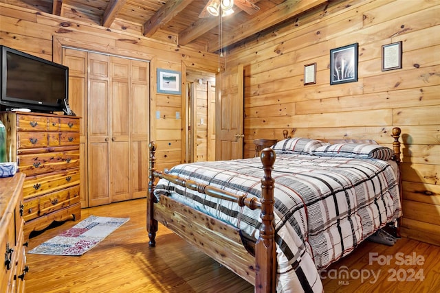 bedroom with light hardwood / wood-style floors, wood walls, wooden ceiling, ceiling fan, and beam ceiling