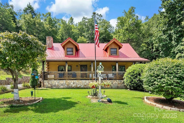 view of front of home with covered porch, a chimney, a front lawn, and metal roof