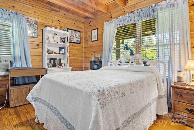 bedroom with wood finished floors, beam ceiling, wood walls, and wooden ceiling