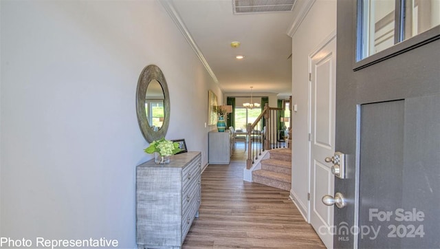 entrance foyer featuring ornamental molding, a chandelier, and light hardwood / wood-style flooring