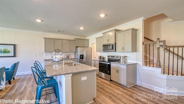 kitchen with sink, gray cabinets, stainless steel appliances, and an island with sink