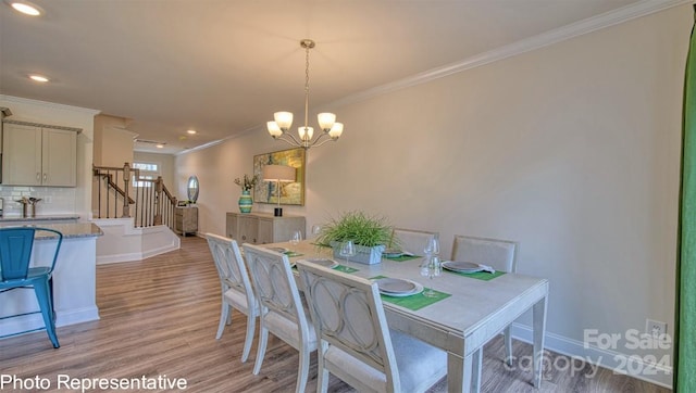 dining space with an inviting chandelier, ornamental molding, and light wood-type flooring