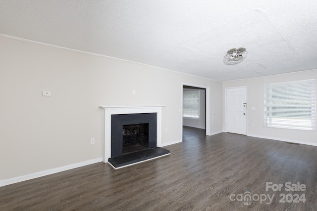 unfurnished living room featuring dark hardwood / wood-style flooring and a textured ceiling