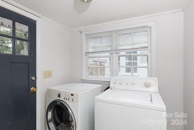 clothes washing area with ornamental molding, washer and dryer, and a textured ceiling