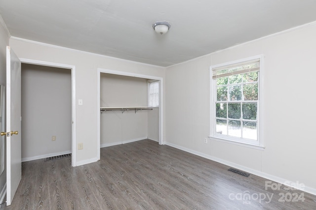 unfurnished bedroom featuring ornamental molding, dark hardwood / wood-style floors, and a closet