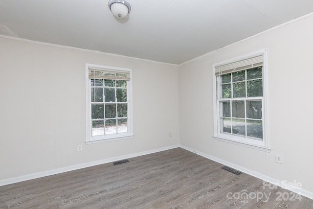 empty room with hardwood / wood-style flooring and ornamental molding