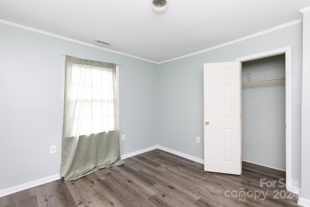 unfurnished bedroom with crown molding, dark hardwood / wood-style floors, and a closet