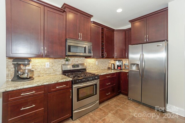 kitchen featuring light stone counters, stainless steel appliances, backsplash, and light tile patterned floors