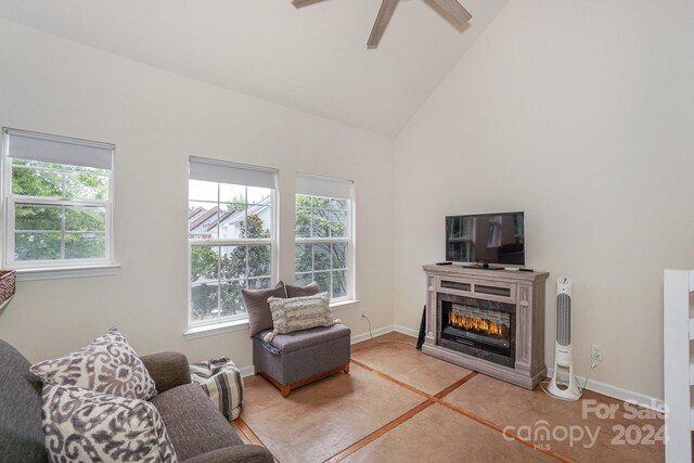 living room with ceiling fan, a fireplace, and high vaulted ceiling