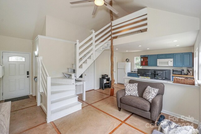 living room with ceiling fan and a towering ceiling