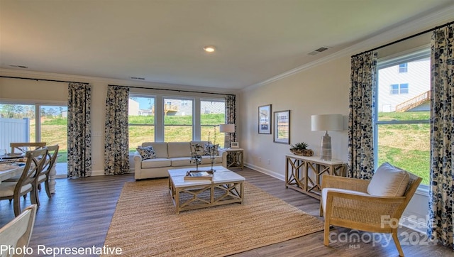 living area with a wealth of natural light, wood finished floors, visible vents, and crown molding