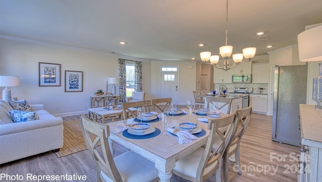 dining space with light wood finished floors, recessed lighting, an inviting chandelier, ornamental molding, and baseboards