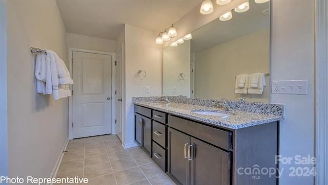 bathroom with baseboards, double vanity, a sink, and tile patterned floors