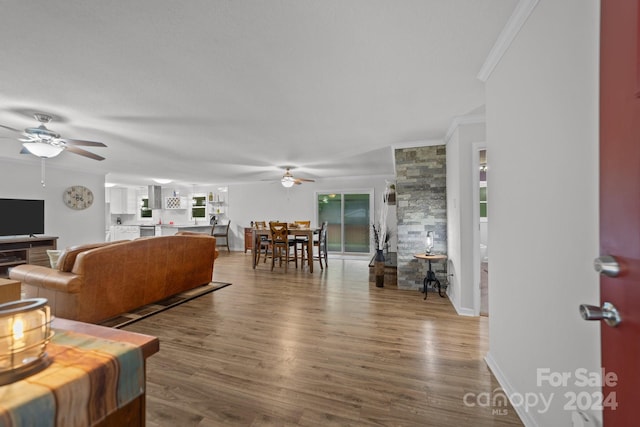 living room featuring hardwood / wood-style floors, ornamental molding, and ceiling fan