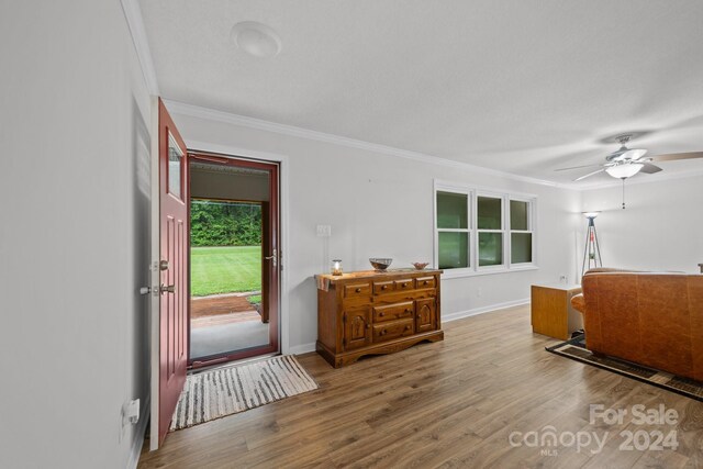 foyer entrance featuring wood-type flooring, crown molding, and ceiling fan