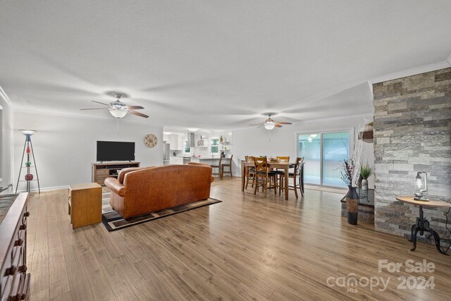 living room with light hardwood / wood-style floors, ornamental molding, and ceiling fan