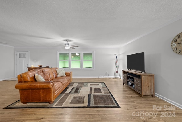 living room with ceiling fan, light hardwood / wood-style flooring, ornamental molding, and a textured ceiling