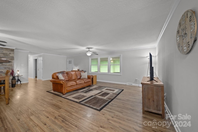 living room featuring ceiling fan, ornamental molding, hardwood / wood-style floors, and a textured ceiling