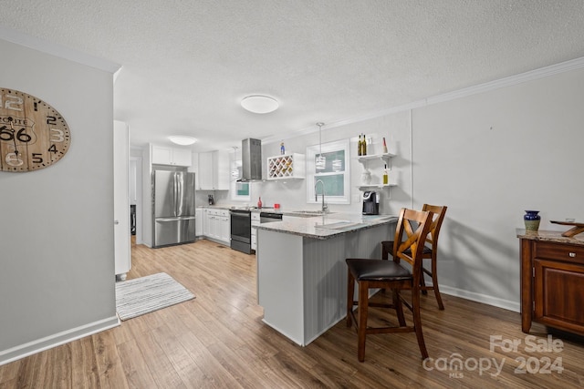 kitchen with a kitchen bar, sink, kitchen peninsula, stainless steel appliances, and wall chimney range hood