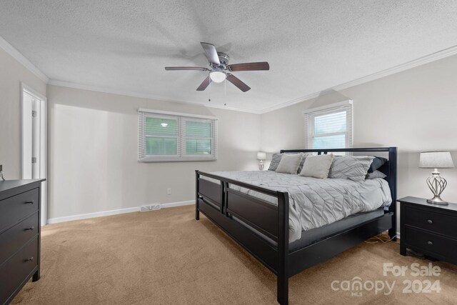 carpeted bedroom with a textured ceiling, ceiling fan, and crown molding