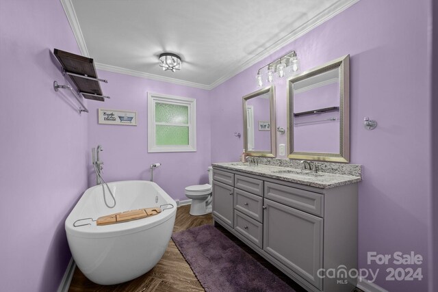 bathroom with ornamental molding, toilet, a tub to relax in, and double sink vanity