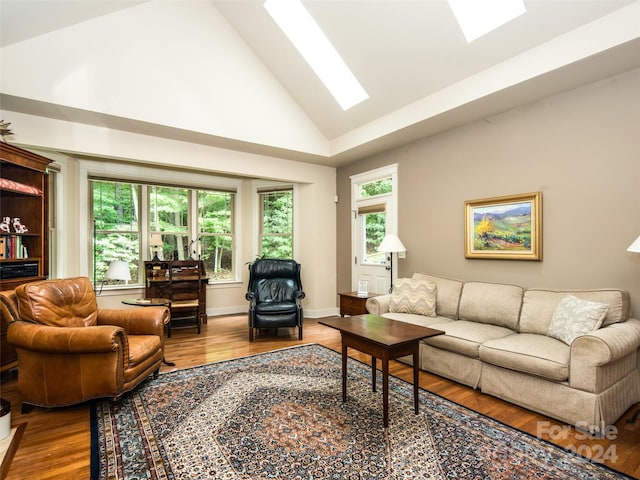 living room with hardwood / wood-style floors, a wealth of natural light, a skylight, and high vaulted ceiling